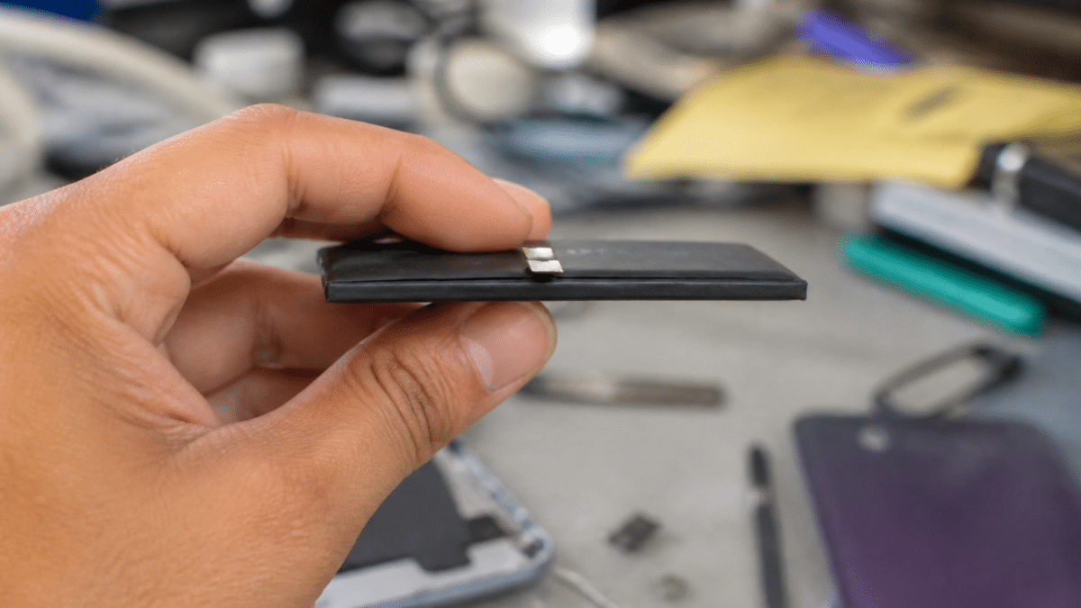 Technicien tenant batterie iPhone 11 detachee horizontalement