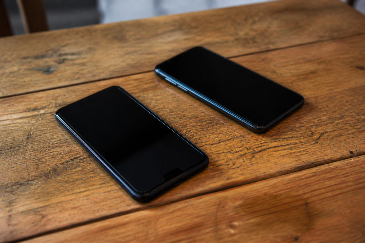 Deux smartphones noirs poses sur table en bois