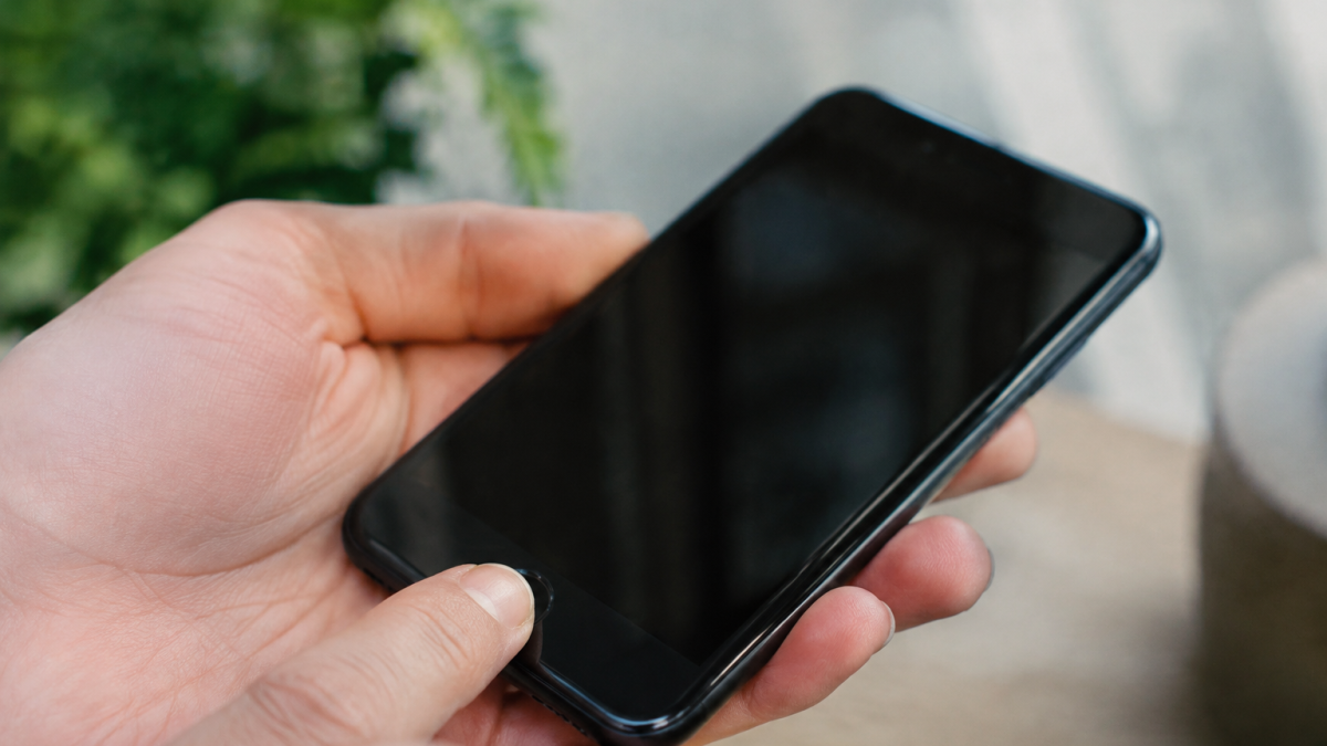 Doigt appuyant sur un bouton rond d'un smartphone noir
