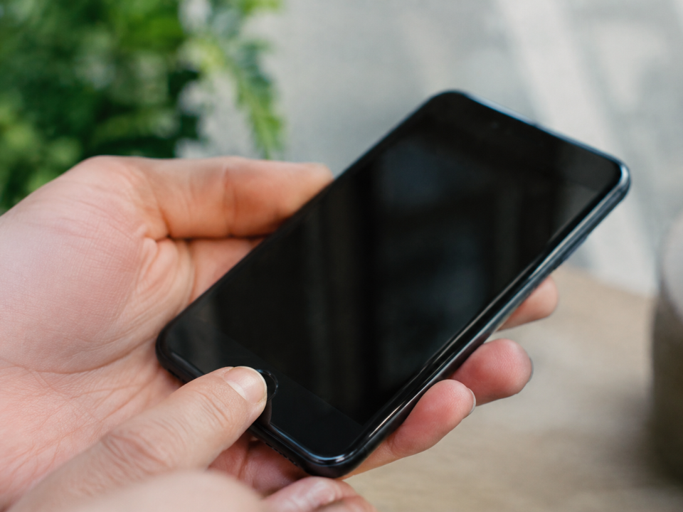 Doigt appuyant sur un bouton rond d'un smartphone noir