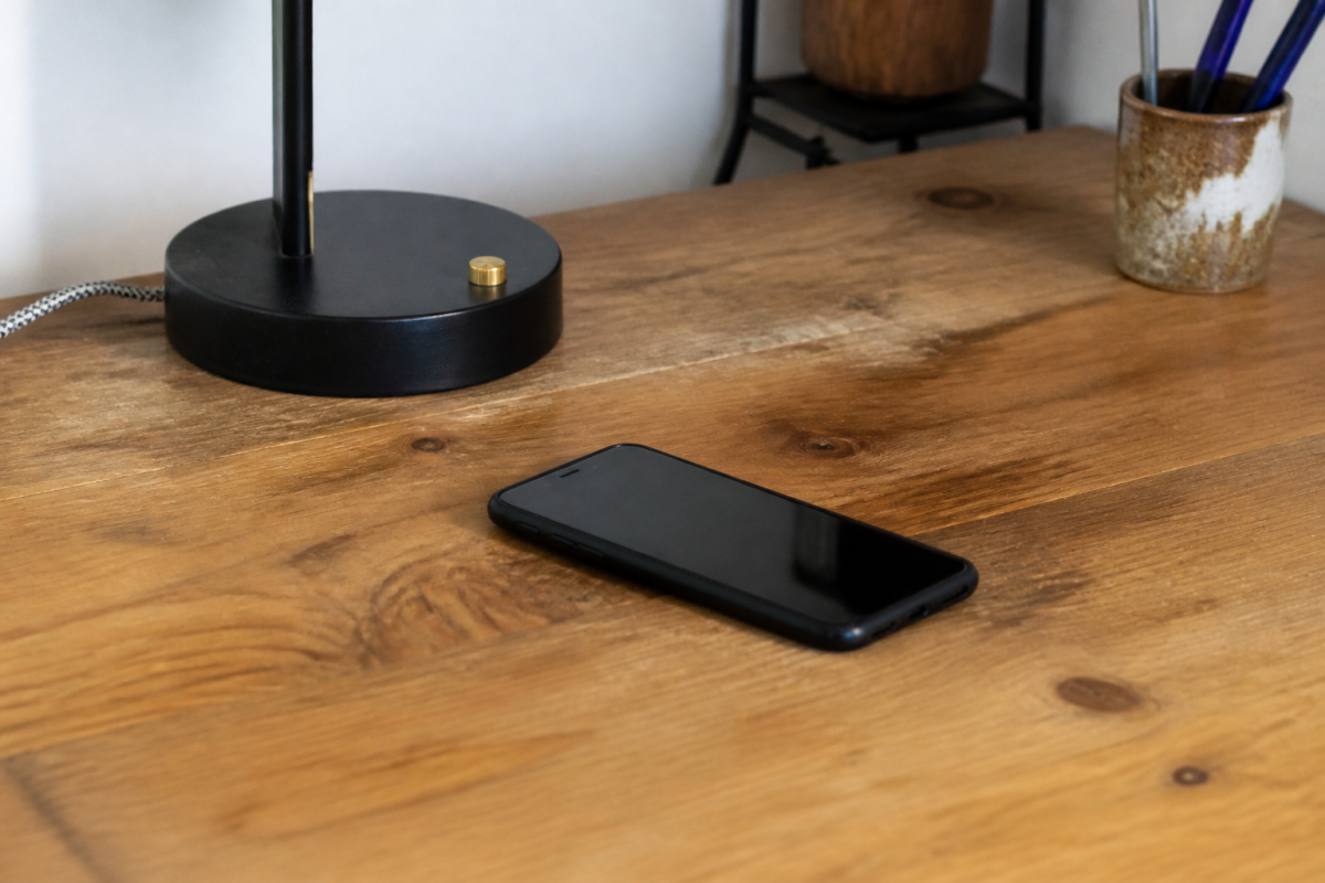 Smartphone noir sur un bureau en bois avec lampe