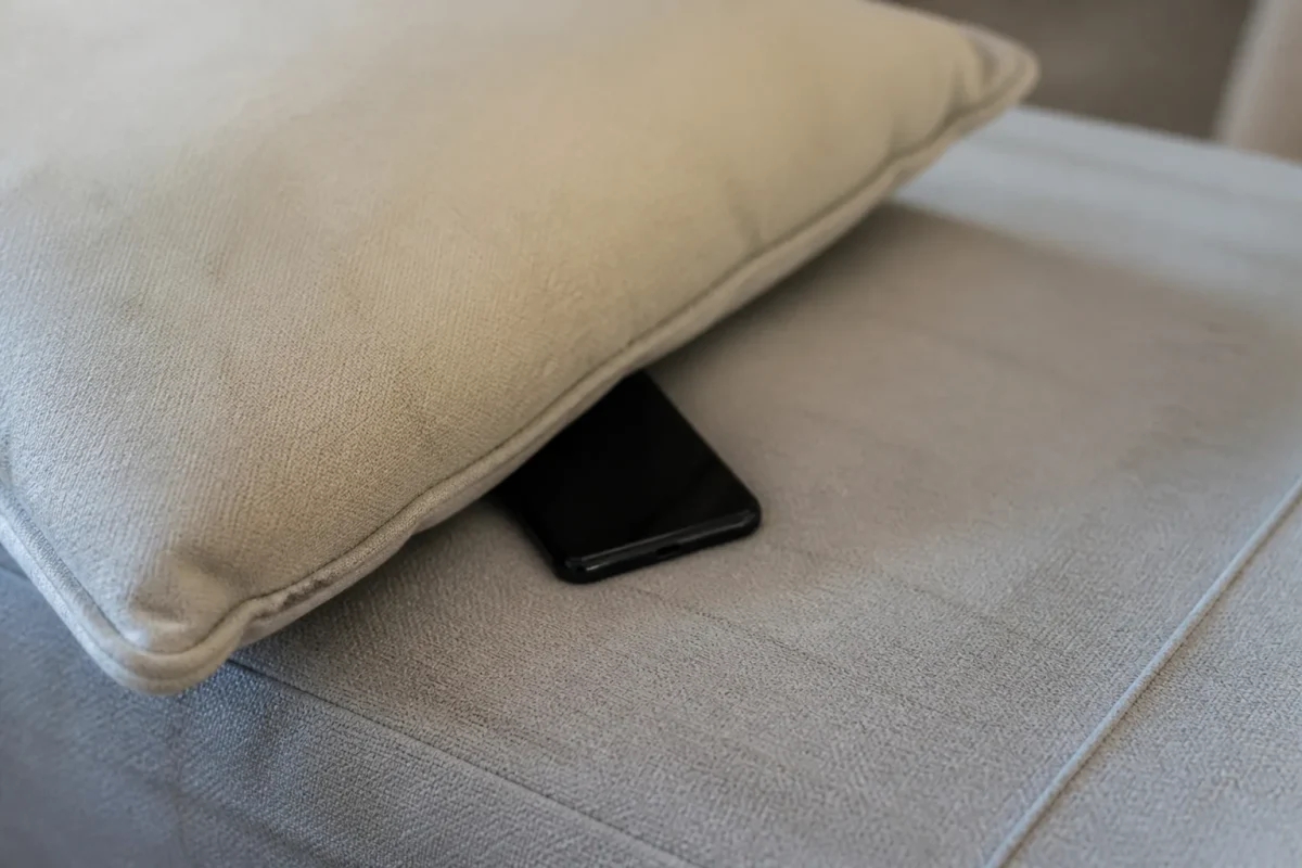 Smartphone noir glissé sous un coussin beige