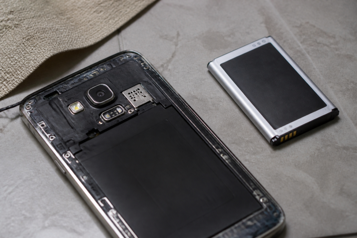 Smartphone ouvert et accu neuf pose sur une table